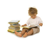 small boy reading a book from a pile of books
